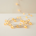 Illustrative frosted mini globe LED string lights with a warm golden glow