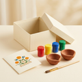 Illustrative kit with two plain terracotta diyas, four paint pots, one brush, greeting card and gift box