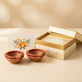 Illustrative Diwali return gift set with two decorative diyas, greeting card and open gift box